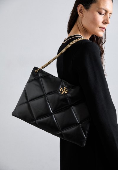Sac à main noir matelassé en matériau brillant, avec une bandoulière en chaîne dorée et un accent décoratif avec logo. Forme rectangulaire.