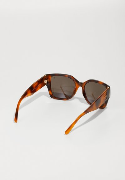 Tortoiseshell päikeseprillid tumedate läätsedega. Julge ristkülikukujuline raam. Sile tekstuur, nurkadega disain ja logo detail tempel.
