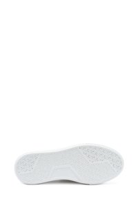 Sole di sneaker bianca con una base in gomma testurizzata caratterizzata da un intricato motivo ondulato e una punta arrotondata. Design minimalista, senza branding visibile.