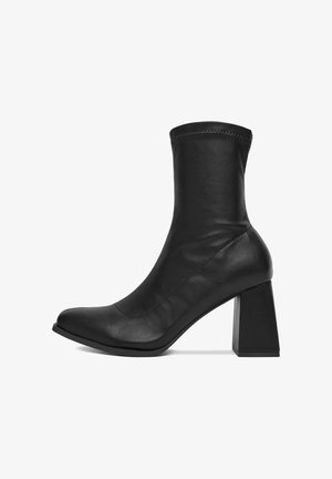 Čierne kožené členkové topánky s okrúhlou špičkou, vysokým zvrškom a masívnym štvorcovým podpätkom. Hladký povrch s minimálnymi švovými detailmi.