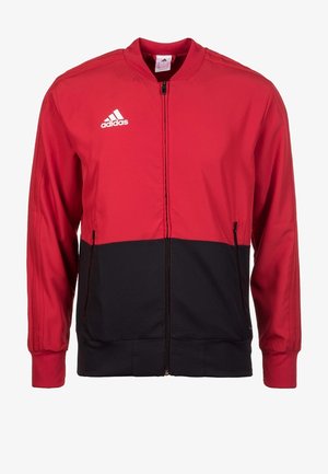 Chaqueta de cremallera roja y negra con un alto cuello, mangas largas y el logo blanco de Adidas en el lado izquierdo del pecho. Tela suave con puños acanalados.