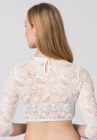 Weißes Spitzen-Crop-Top mit langen Ärmeln, verziert mit floralen Mustern, zarter Textur und einem Schlüsselaugenverschluss hinten mit einem Knopfdetail.