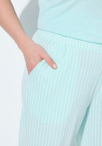 Pantalones rayados azul claro hechos de una tela suave, con un bolsillo lateral, cinturilla elástica y un corte relajado.