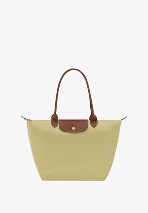 Tote bag in light yellow nylon with brown leather handles and a top flap closure featuring a gold logo. Smooth, water-resistant texture.