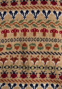 Varrustatud kootud kangas, mis esitleb mitmevärvilist mustrit punastest seentest, sarapuupähklitest ja rebaseid tan taustal, tumedate siniste ja roheliste aktsentidega.