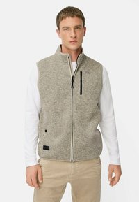 Grau fleece Weste mit hohem Kragen, Vorderreißverschluss und schwarzem Reißverschlussfach. Getragen über einem weißen Langarmshirt und beigen Hosen.