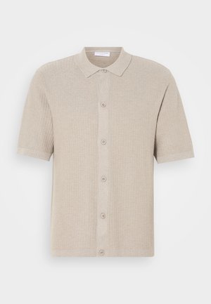 Beige lyhythihainen neulecardigan, jossa on teksturoitu kuvio, napitettava etuosa sekä ribbaus kauluksessa ja helmassa. Ominaisuutena viisi nappia samassa sävyssä.