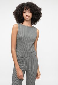 Sort og hvidt houndstooth-mønstrede ærmeløse top med en tætsiddende silhuet og rund udskæring, parret med matchende bukser.