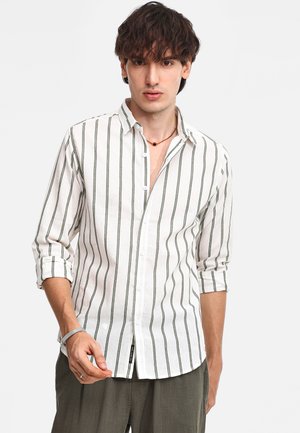 Camicia bianca con righe verticali verdi, maniche lunghe arrotolate, tessuto strutturato e vestibilità casual. Dettagliata con un colletto.