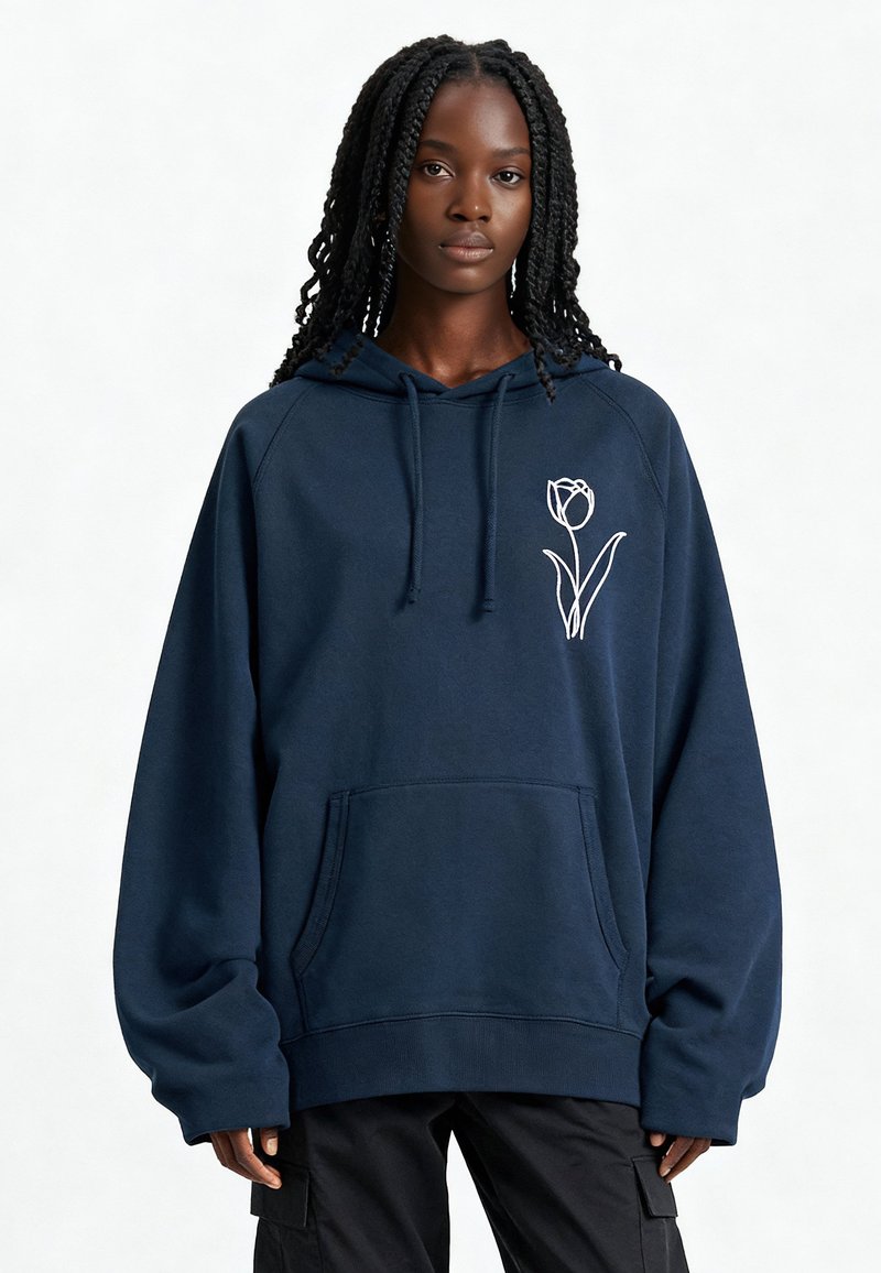 Sweat à capuche bleu marine avec cordon de serrage, grande poche avant et motif de tulipe blanche sur le côté gauche de la poitrine. Fabriqué à partir d'un matériau doux et texturé.