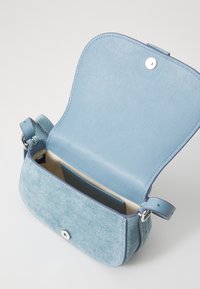 Borsa blu con corpo in denim testurizzato e patta in pelle liscia. Presenta una chiusura a scatto e una tracolla. L'interno mostra un portacarte.