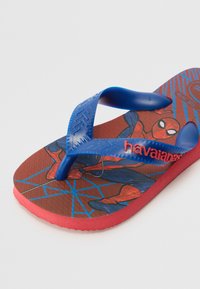 Blå gummisandal med et Spider-Man-motiv på en rød og sort såle, teksturerte stropper og en polstret fotseng.