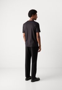 Black short-sleeve shirt with a straight cut, paired with black trousers. Smooth fabric with a simple design, no visible patterns or accents.