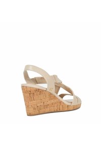 Beige wedge sandaal met kurken platform, met gekruiste bandjes en een gouden accent. Gladde textuur en open ontwerp voor ademend vermogen.