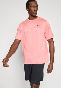 Αθλητική μπλούζα κοντομάνικη σε ανοιχτό ροζ χρώμα με υφή σχεδίου. Σκούρο μπλε λογότυπο στο στήθος. Συνδυάζεται με μαύρο αθλητικό σορτς. Άνετη εφαρμογή.