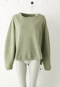 Lysegrønn ribbete langermet crewneck-genser med senkede skuldre vist på en hvit mannequin-torso mot en ensfarget bakgrunn.