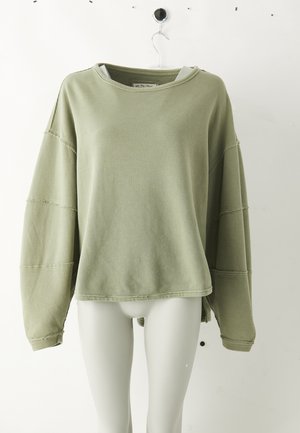 Light green ribbed long-sleeve crewneck top with dropped shoulders displayed on a white mannequin torso against a plain background.