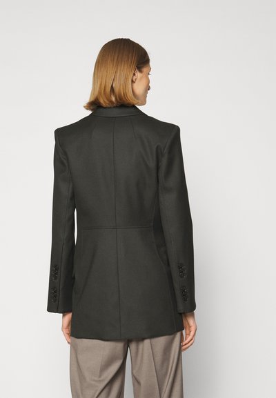 Zwarte op maat gemaakte blazer met gestructureerde schouders, lange mouwen en knoopmanchetten. Gladde textuur met achternaaddetail en minimalistisch ontwerp.