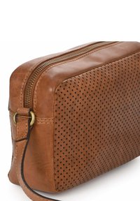 Korte leren crossbody tas in bruin met geperforeerde textuur, gouden rits, rechthoekige vorm, korte schouderband en gladde afwerking.