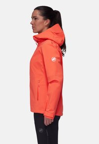Veste imperméable orange vif avec capuche, poche zippée à l'avant et patch logo, présentant un design élégant et ajusté ainsi qu'une texture lisse.