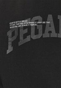 Tessuto nero con grande testo grigio audace che recita "PEGA" con un testo bianco più piccolo sopra, che trasmette frasi motivazionali.