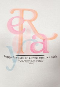 T-shirt en coton blanc avec un texte coloré superposé en rose et orange, accompagné d'une citation en dessous. Le design est ludique et moderne.