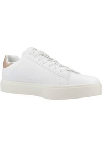 Zapatilla de piel blanca con un acabado suave, punta redondeada y suela blanca texturizada; presenta un acento metálico dorado en el talón.