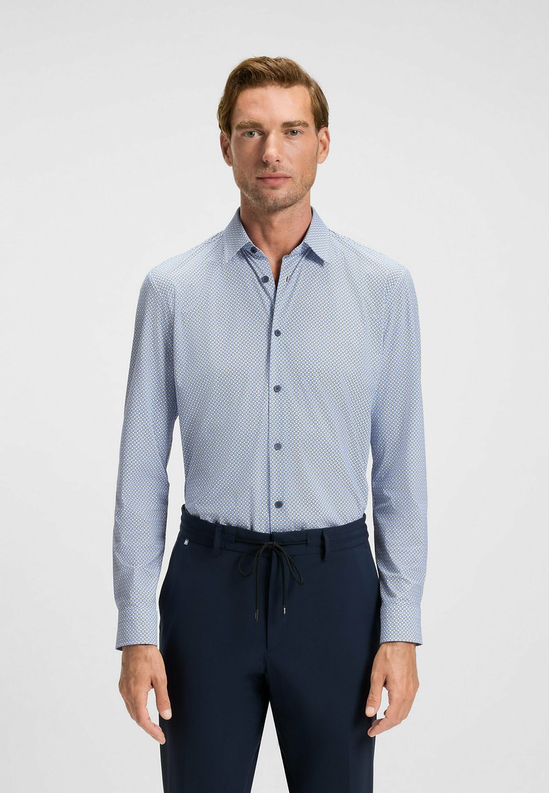 Camicia a maniche lunghe a quadri blu chiaro con accenti blu scuro, realizzata in un tessuto liscio, abbinata a pantaloni tapered blu navy con vita regolabile.