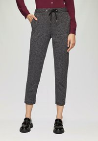 Pantalons courts gris texturés avec une taille à cordon, poches latérales et un motif chevron subtil, associés à des mocassins noirs.