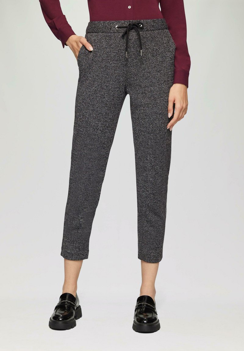 Pantalons courts gris texturés avec une taille à cordon, poches latérales et un motif chevron subtil, associés à des mocassins noirs.