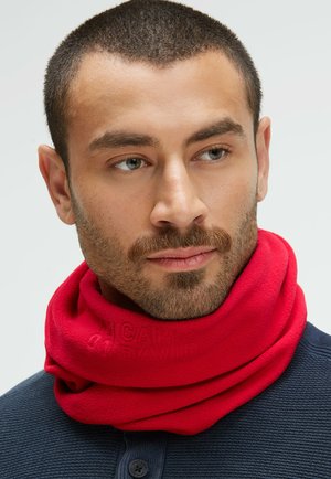 Red fleece neck warmer with a textured finish, featuring subtle embossed branding. Worn loosely around the neck against a navy shirt.