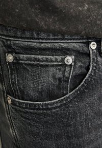 Čierne džínsy z denimu s textúrovaným povrchom, klasickým päťvreckovým dizajnom, nitmi striebornej farby a kontrastným prešitím.