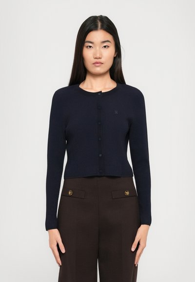 Mørkeblå ribbet cardigan med lange ærmer, rund halsudskæring og knapper foran. Har en tekstureret finish og logo detalje på brystet.