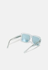 Ochelari de soare transparenti cu lentile de un albastru deschis, ramă rectangulară și brațe sub�țiri din metal. Accente reflectorizante notabile pe laterale.