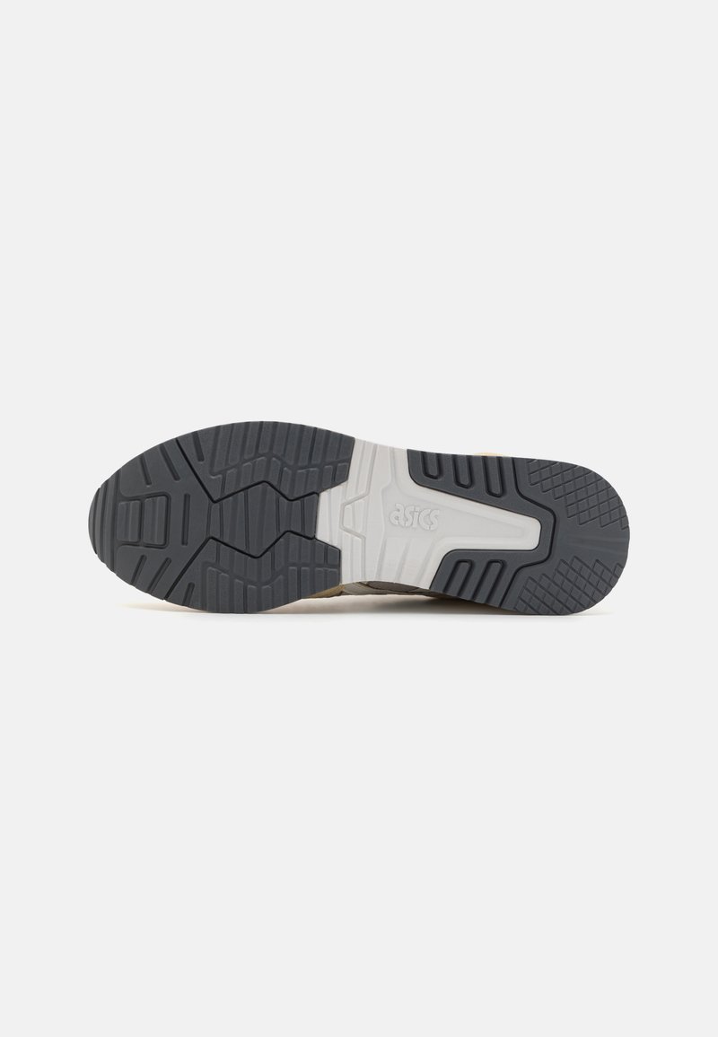 Suela de zapatilla de running con un material de goma texturizado en gris oscuro y una mediasuela blanca. El patrón de la pisada proporciona agarre y estabilidad.