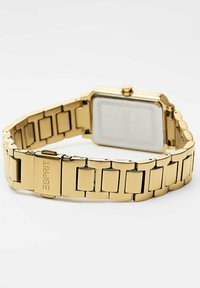 Orologio dorato con quadrante rettangolare e bracciale in metallo a maglie. Design minimale, texture liscia, presenta un logo inciso sulla cinturino.