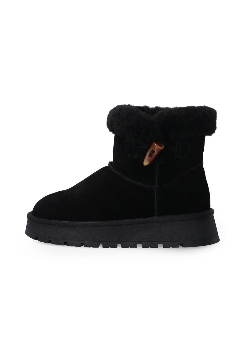 Černé semišové kotníkové boty mají kožený lem z kožešiny, boční zapínání na šňůrku a texturovanou gumovou podrážku pro lepší trakci.