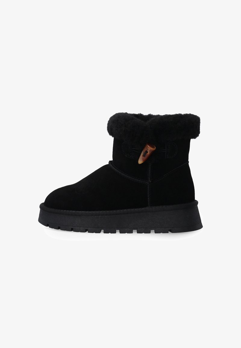 Černé semišové kotníkové boty mají kožený lem z kožešiny, boční zapínání na šňůrku a texturovanou gumovou podrážku pro lepší trakci.