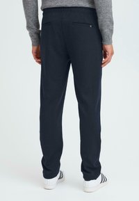 Mornarice z elastičnim pasom, ravnim krojem in dvema zadnjima žepoma. Narejene iz teksturirane tkanine, z diskretnimi oblikovalskimi detajli.