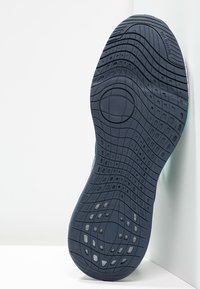 Suola in gomma blu scuro con motivi scanalati texturizzati, accenti circolari e bordo liscio, progettata per trazione e durabilità.