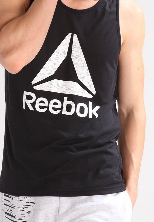 Black tank top made of cotton with a large white Reebok logo and a triangular graphic design. Smooth texture and regular fit.