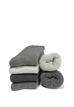 Ein Stapel aus fünf gefalteten und zwei gerollten grauen und hellgrauen Socken, arrangiert auf weißem Hintergrund.