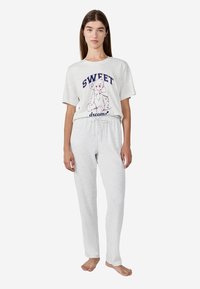 Lichtgrijs pyjama set met een t-shirt met korte mouwen met een beerafbeelding en de tekst "SWEET dreams", gecombineerd met bijpassende broek met koord.