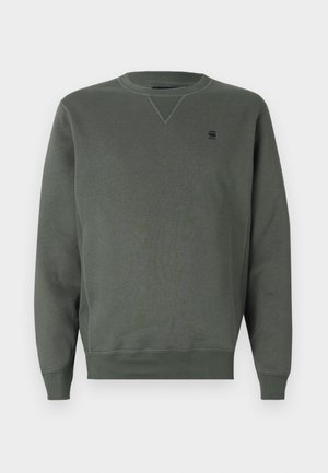 Sweatshirt verde cu guler rotund realizat dintr-un material moale, având o cusătură triangulară la guler și un mic logo brodat pe piept.