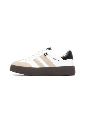 Zapatilla blanca con acentos en beige y negro. Presenta una puntera de ante, un diseño de tres rayas y una gruesa suela de caucho negro.