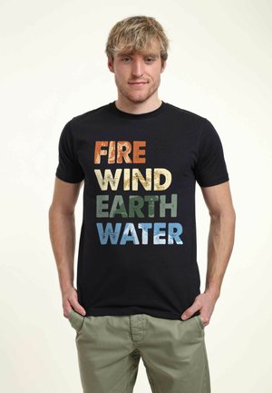 Sort bomulds t-shirt med et grafisk print, der viser ordene "FIRE," "VIND," "JORD," og "VAND" i forskellige farver og teksturer.