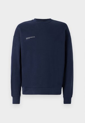 Sweatshirt bleu marine en tissu doux, avec un col rond, des manches longues et un petit détail en texte blanc sur le devant.