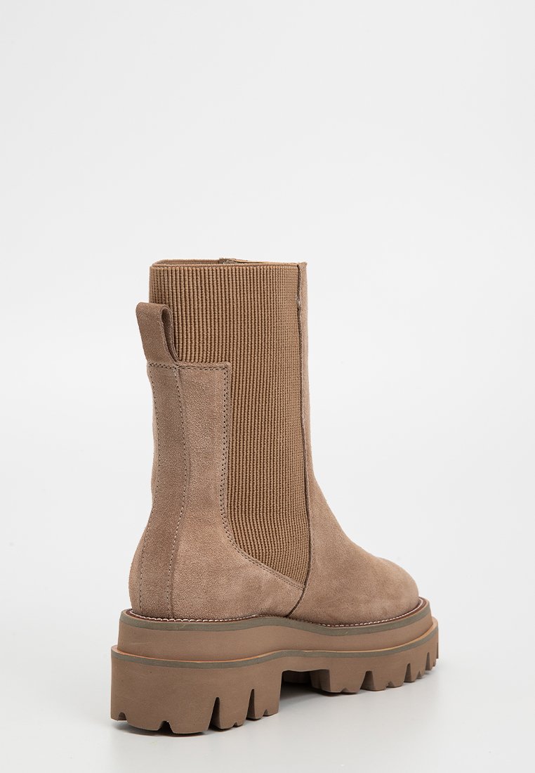 Braune Wildleder-Stiefeletten mit einem gerippten, elastischen Seitenpanel, einer stabilen Gummisohle und einer Lasche an der Rückseite für ein einfaches Anziehen.