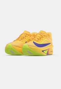 Gule løpesko med mesh-overdel, lilla detaljer og grønn såle. Har en polstret design og en karakteristisk platåform.