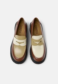 Loafers met een bovenwerk van bruin leer, een beige lederen band met een uitsnijding en een stevige zwarte rubberen zool.